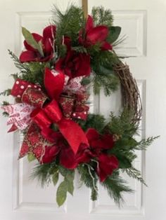 a christmas wreath hanging on a door with red bows and greenery in front of it