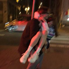 a man and woman kissing on the street at night