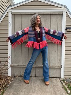 a woman standing in front of a garage door with her arms spread out and wearing a scarf