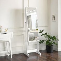 a white dressing table with a mirror on it and a potted plant next to it