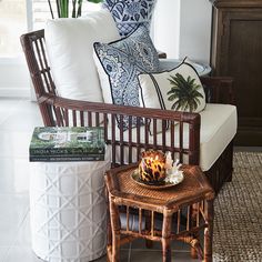 a wicker chair sitting next to a table with a candle on top of it