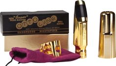 a pair of gold and black lipsticks next to a purple bag with pink lining