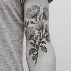 a man's arm with flowers and leaves tattooed on the back of his arm