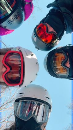 three people wearing helmets and goggles standing in a circle