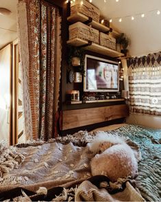 a dog laying on top of a bed in front of a tv mounted to the wall