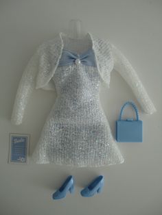 a white dress and blue shoes are on the table next to a small handbag