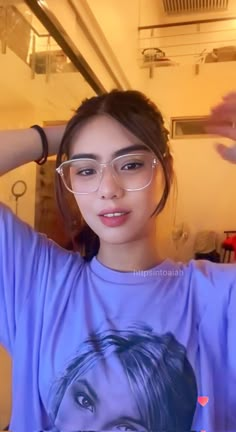 a young woman wearing glasses and looking at the camera with her hands behind her head