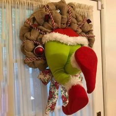 a christmas wreath hanging from the side of a door with stockings and hats on it