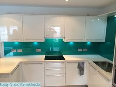 an empty kitchen with white cabinets and green backsplashes on the wall,