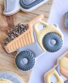 cookies decorated like tractors and trucks on top of a wooden table next to cookie cutters