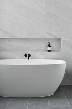 a white bath tub sitting on top of a tiled floor