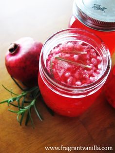 two jars filled with liquid sitting on top of a table next to apples and rosemary