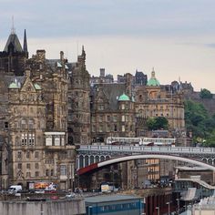 an old castle like building with a bridge in the foreground and cars parked on the street below