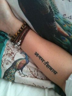 a woman's arm with a peacock tattoo on it, and the word india written in two different languages