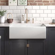 a white kitchen sink sitting under a faucet next to a counter top with potted plants on it