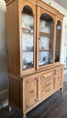 a wooden china cabinet with glass doors and drawers