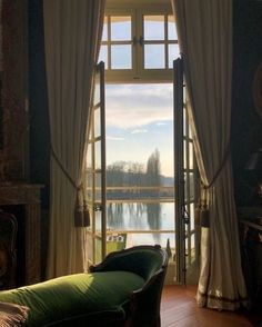 a living room filled with furniture and a large window overlooking a body of water in the distance