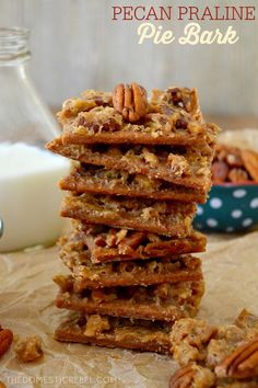 pecan pralie pie bark is stacked on top of each other and next to a glass of milk