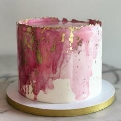 a pink and gold cake sitting on top of a white plate next to a marble counter