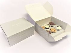 four cupcakes in a box on a white surface