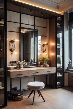 a dressing table and stool in a room with large mirrors on the wall above it