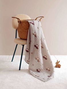 a baby blanket sitting on top of a chair next to a stuffed animal and basket