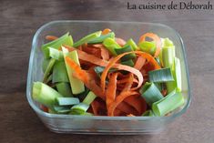 a plastic container filled with carrots and celery on top of a wooden table