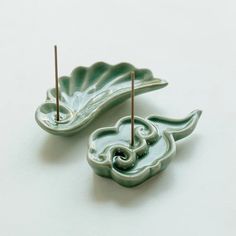 two decorative objects sitting on top of a white table next to each other and sticks sticking out of them