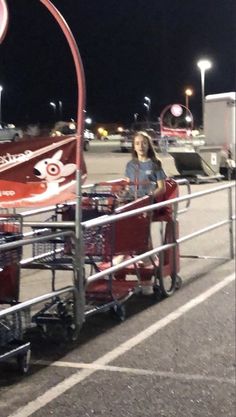 a woman standing next to a red car in a parking lot