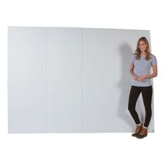 a woman standing in front of a white wall with her hands on her hips and looking at the camera