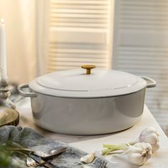 a large white pot sitting on top of a table next to a candle and garlic