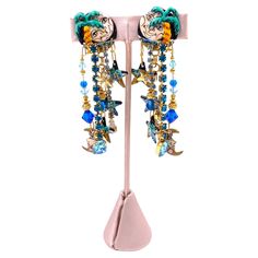 Add a touch of whimsy to your outfit with our Lunch at the Ritz Earrings, Moon Over Miami. Featuring a painted moon and stars detail with blue and gold beading, these dangle earrings are adorned with large rhinestones for an eye-catching look. Perfect for any occasion! Length: 3.5" Width: 1" Painted Moon, Feather Heels, Gown Suit, Earrings Moon, The Ritz, Wedding Guest Shoes, Summer Special, Belt Purse, Moon And Stars