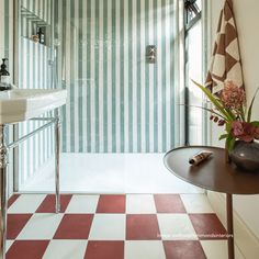 a bathroom with red and white checkered flooring next to a walk in shower