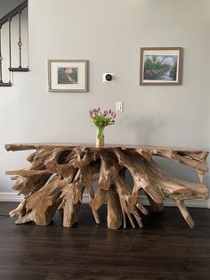 a table made out of driftwood with flowers in a vase on the top and bottom