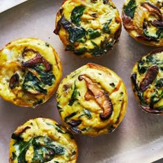 several muffins with spinach and cheese on a tray