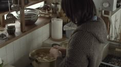 a woman standing in a kitchen preparing food