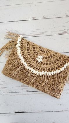 a purse with fringes and beads on the front, sitting on a white wooden surface