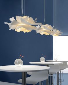 a white table and some chairs with lights hanging from it's ceiling above them