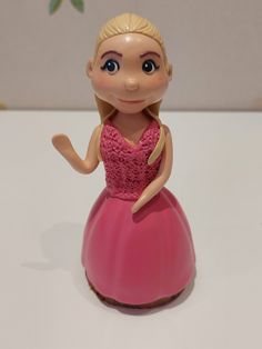 a small toy doll in a pink dress