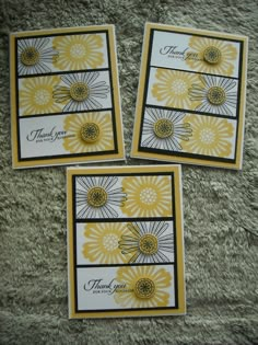 three cards with yellow and white flowers on them are sitting on a carpeted surface