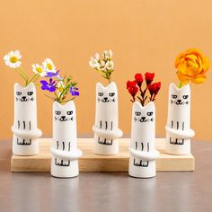 four white cat vases with flowers in them