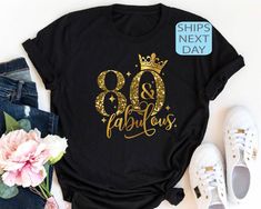 a t - shirt with the words 80 and fabulous on it next to some flowers