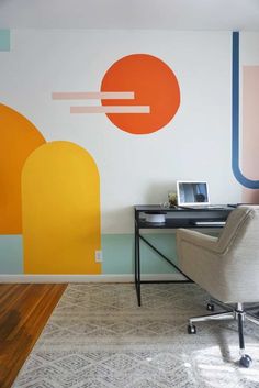 a chair and desk in front of a wall with an abstract painting on it's side