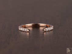 a rose gold ring with five diamonds on a wooden surface, close up view from the side