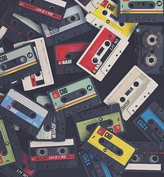 a pile of cassette tapes sitting on top of each other in different colors and sizes