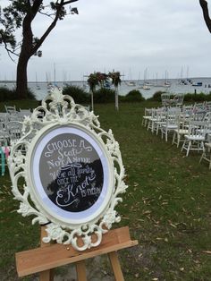 an ornate white frame with chalkboard writing on it in front of rows of chairs