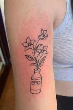 a woman with a tattoo on her arm has a jar with flowers in it and the word love is written below