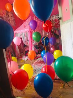 many balloons are floating in the air near a bed and window with curtains on it