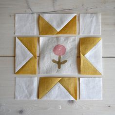 the block is made up of yellow and white fabric with a pink flower on it