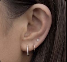 a woman's ear is shown with two small diamond hoops on the side